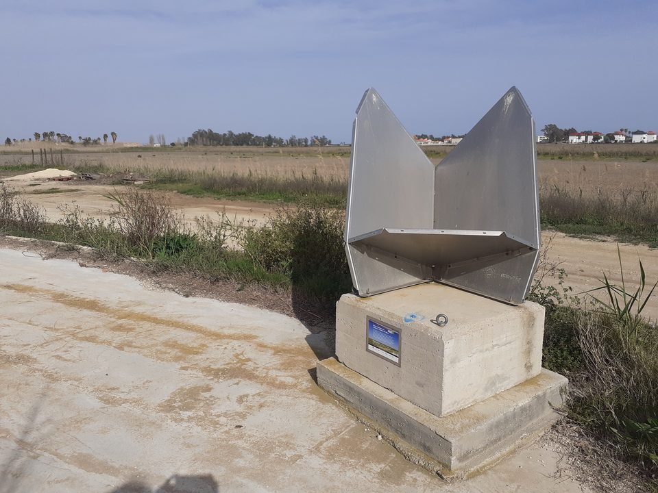 Estructura metálica sobre una base de hormigón con una placa, junto a un camino de la finca