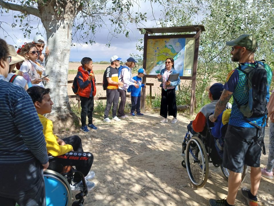 Grupo guiado, con personas en silla de ruedas y niños, ante un panel informativo