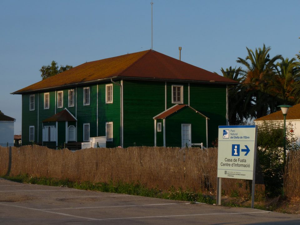 La Casa de Fusta, edificio de madera verde con un cartel de información, en el Delta del Ebro