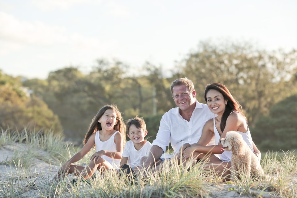Parents and two children sitting together in tall grass