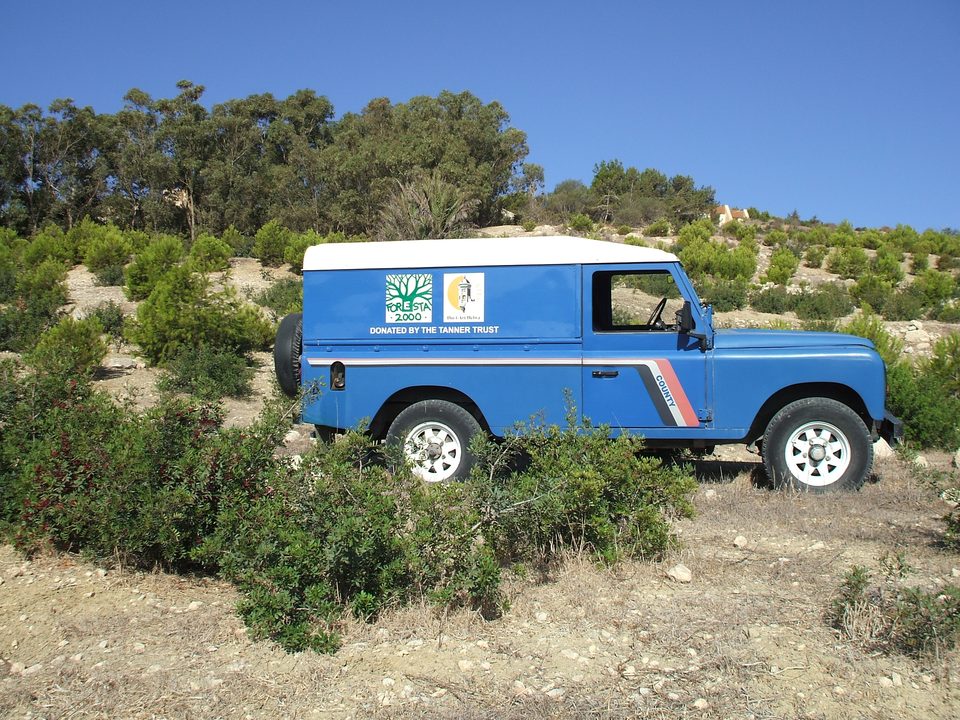 A blue BirdLife Malta Land Rover parked among shrubs