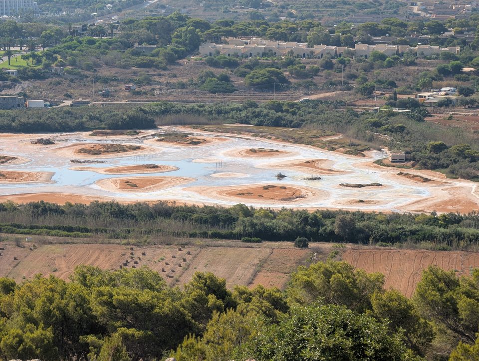 The drying wetland of Għadira seen from above, with pale salt patches