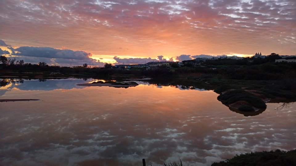 A colourful evening or morning sky reflected in the water at Għadira Nature Reserve