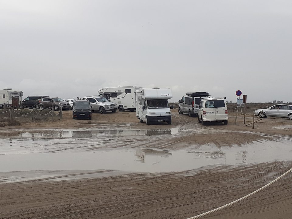 Autocaravanas y coches aparcados en una playa embarrada