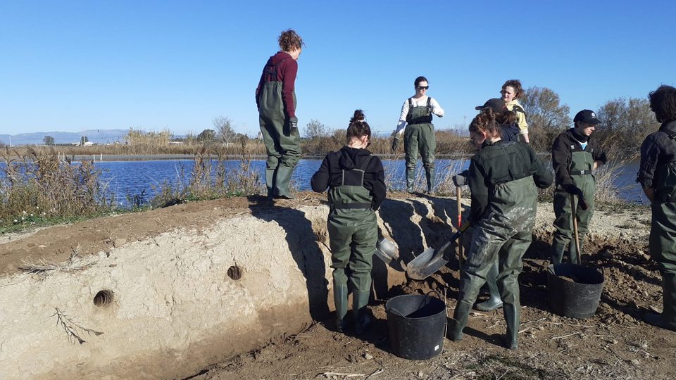 Voluntarios con vadeadores trabajando en un dique junto a la laguna