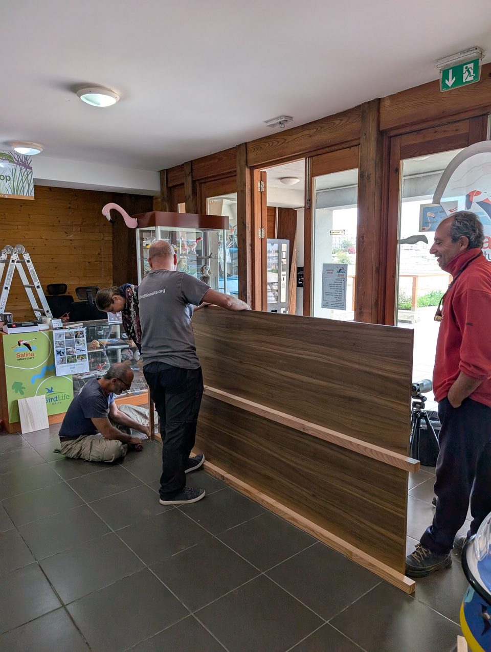 Volunteers moving a wooden counter inside a visitor centre