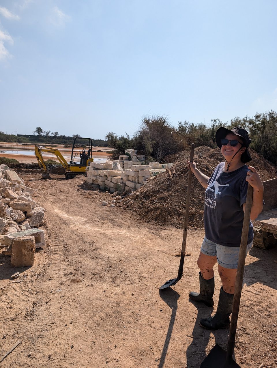 A volunteer with a shovel on a track by the saltpans