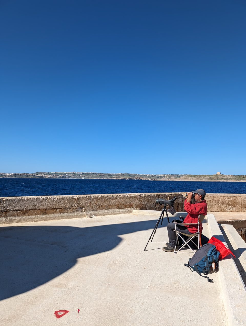 A person with a telescope on a coastal promenade
