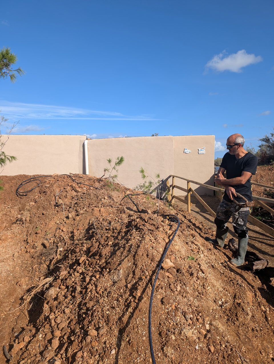 A worker on a mound of earth beside a wall