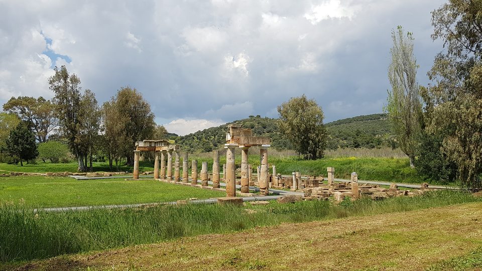 Ο Ναός της Αρτέμιδος στη Βραυρώνα: κίονες μέσα σε πράσινο λιβάδι, με λόφους στο βάθος